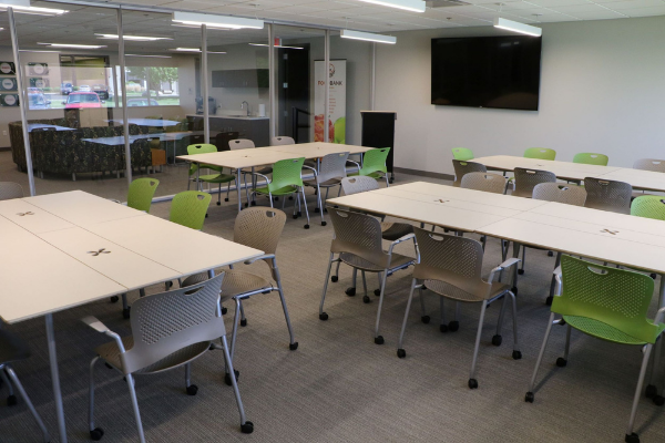 Multi purpose room with 4 tables set up and a tv on the wall